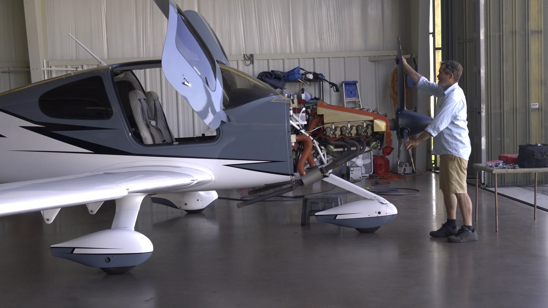 Man working on propeller of airplane with open engine inside hangar