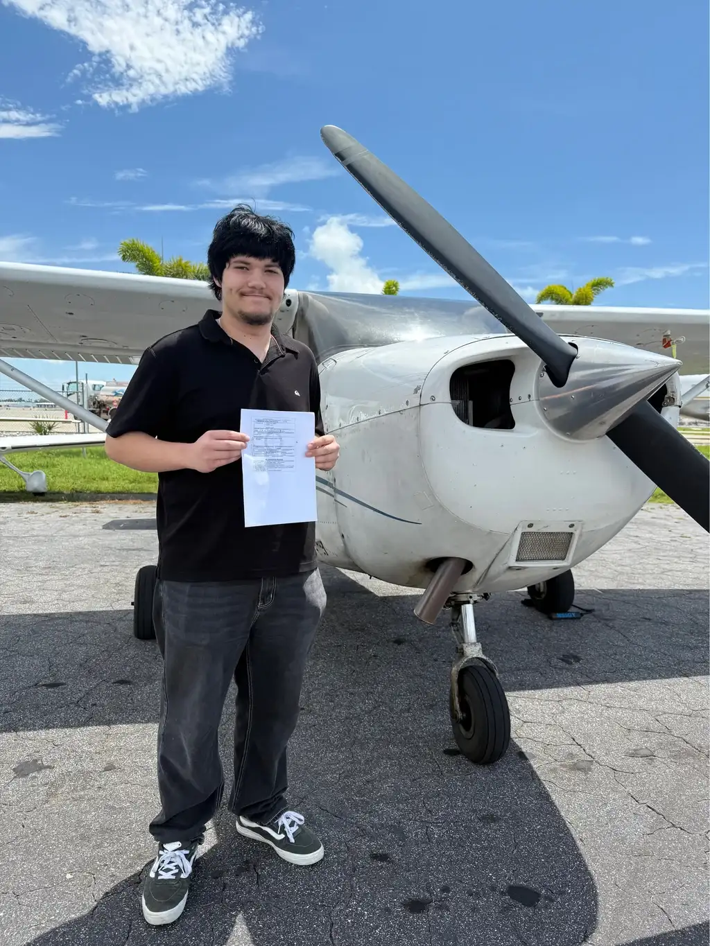 Student holding certificate in front of plane