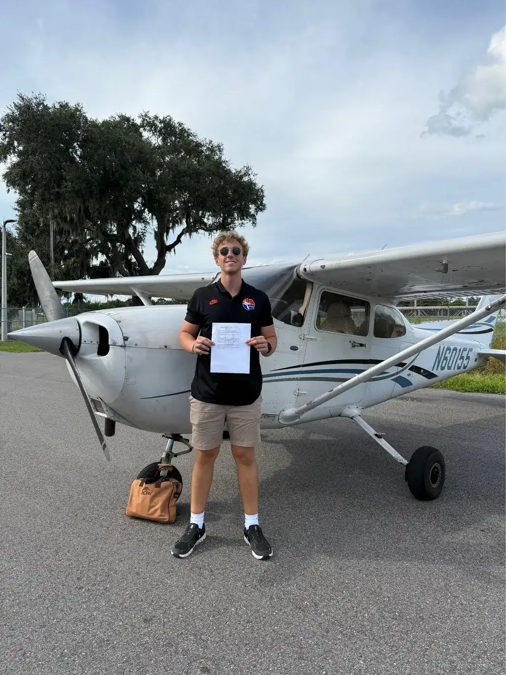 Student holding certificate and smiling in front of aircraft