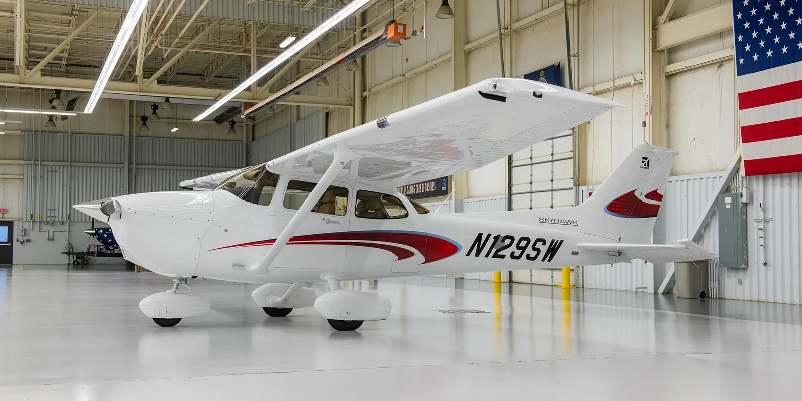 White Cessna 172 Skyhawk training airplane N129SW parked inside a hangar