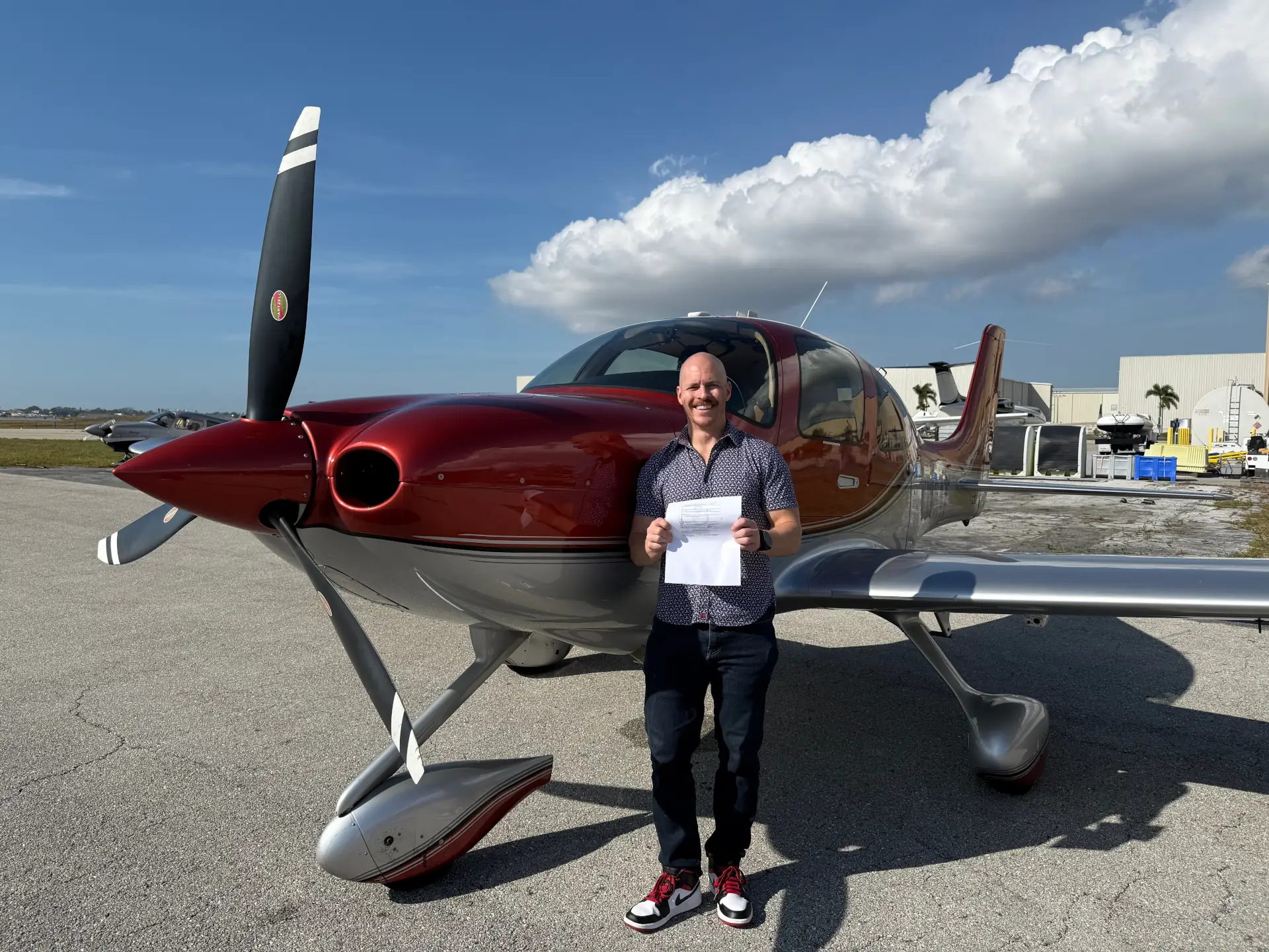 Man holding certificate in front of an airplane