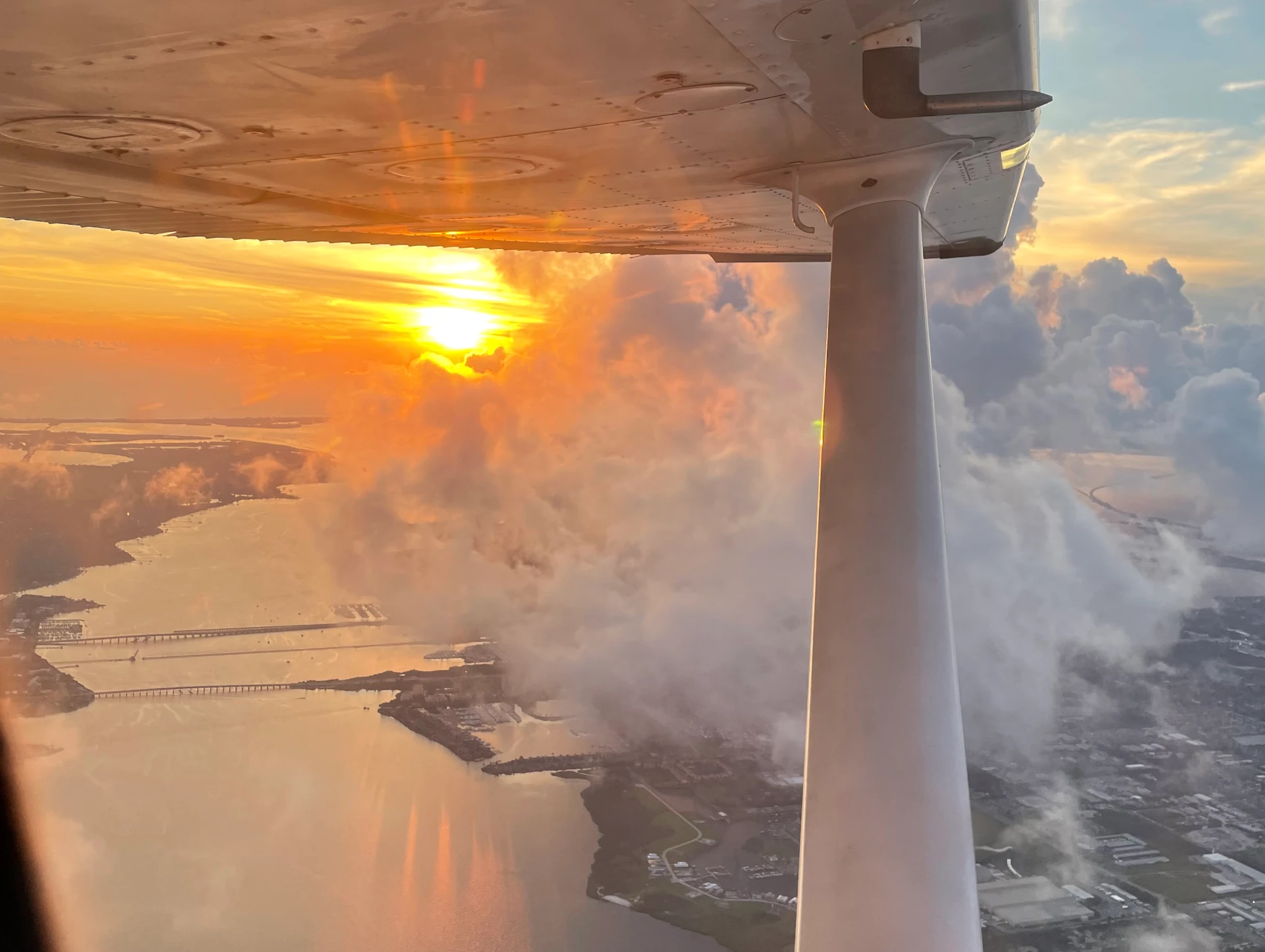 Airplane wing and cockpit view at sunset while flying near Sarasota